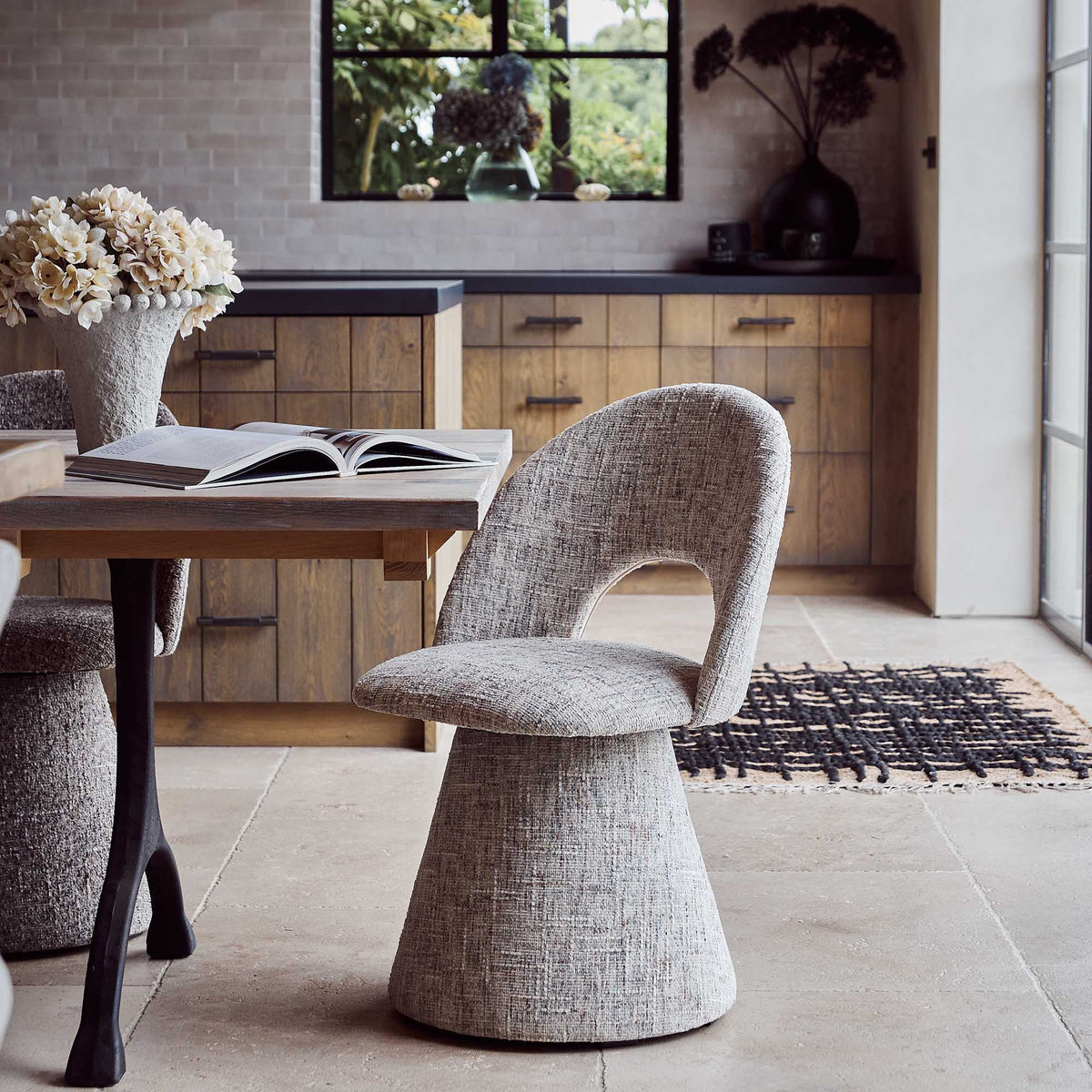 Contemporary upholstered, comfortable dining chair in a textured beige fabric featuring a sculptural curved silhouette a modern but organic design for stylish dining interiors.
