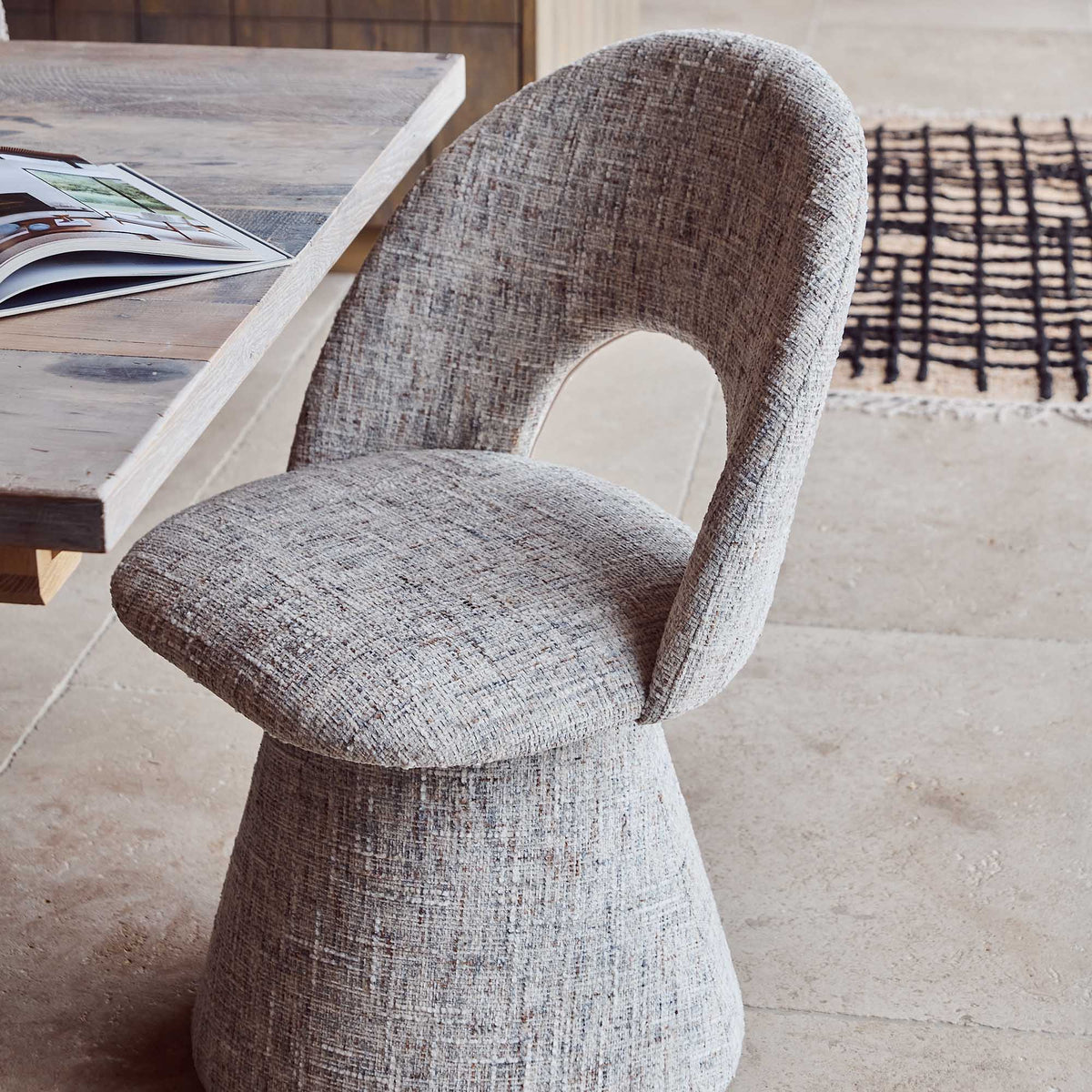 Contemporary upholstered, comfortable dining chair in a textured cream beige fabric featuring a sculptural curved silhouette a modern but organic design for stylish dining interiors.