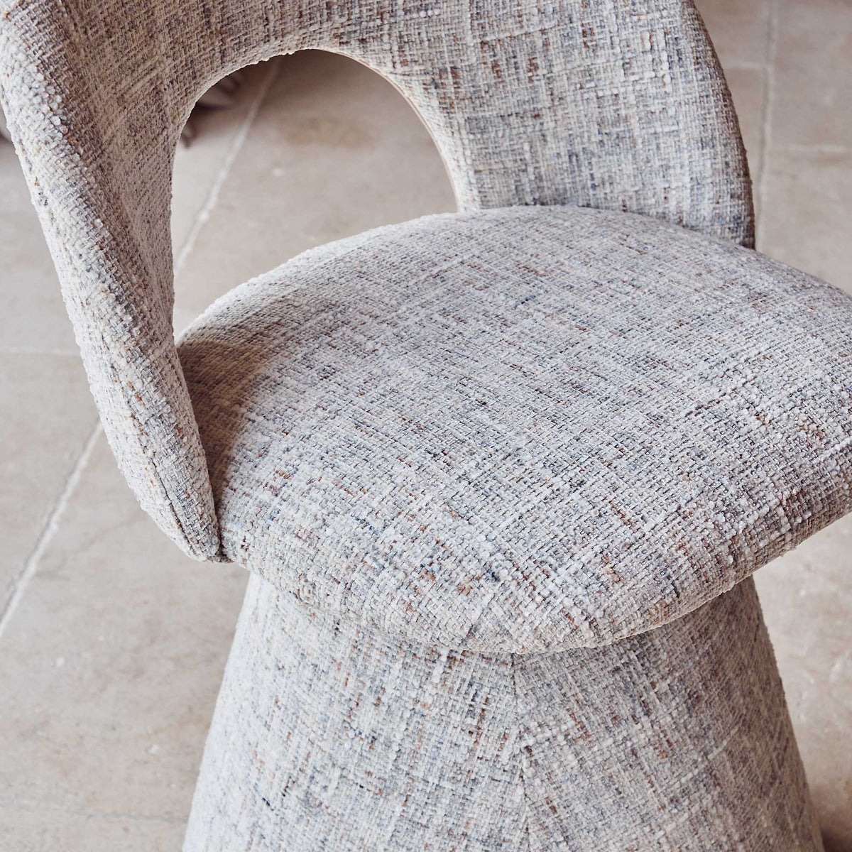 Contemporary upholstered, comfortable dining chair in a textured grey fabric featuring a sculptural curved silhouette a modern but organic design for stylish dining interiors.