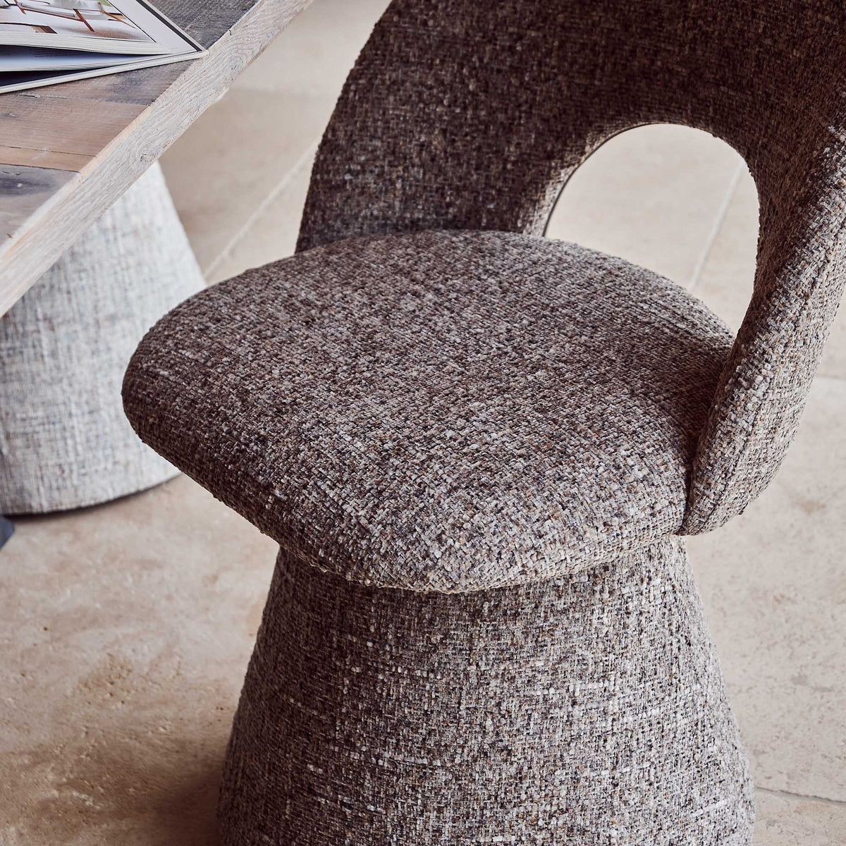 Contemporary upholstered, comfortable dining chair in a textured grey fabric featuring a sculptural curved silhouette a modern but organic design for stylish dining interiors.