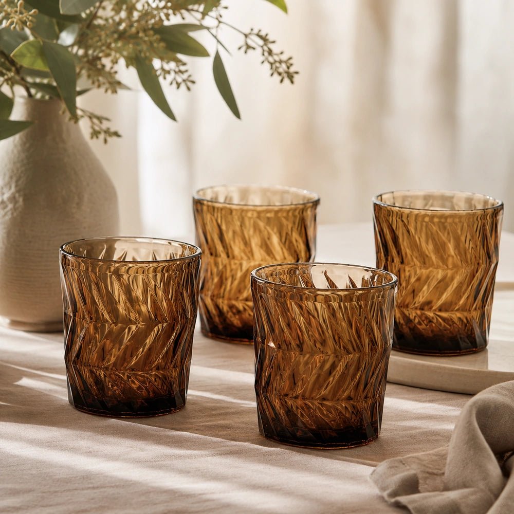 Jackson Drinking Glasses in rich amber patterned glass, styled within a layered place setting with neutral tableware and warm contemporary dining details.
