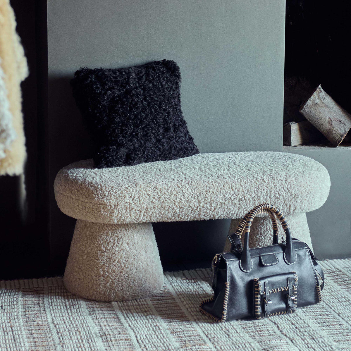 Beige boucle bench with a curved upholstered design and soft textured teddy fabric finish. Tulip boucle bench by Abigail Ahern, a luxury modern seating piece perfect for bedrooms, hallways, living rooms and contemporary interiors. Elegant accent furniture designed to add warmth, comfort and sophisticated style to modern home decor.