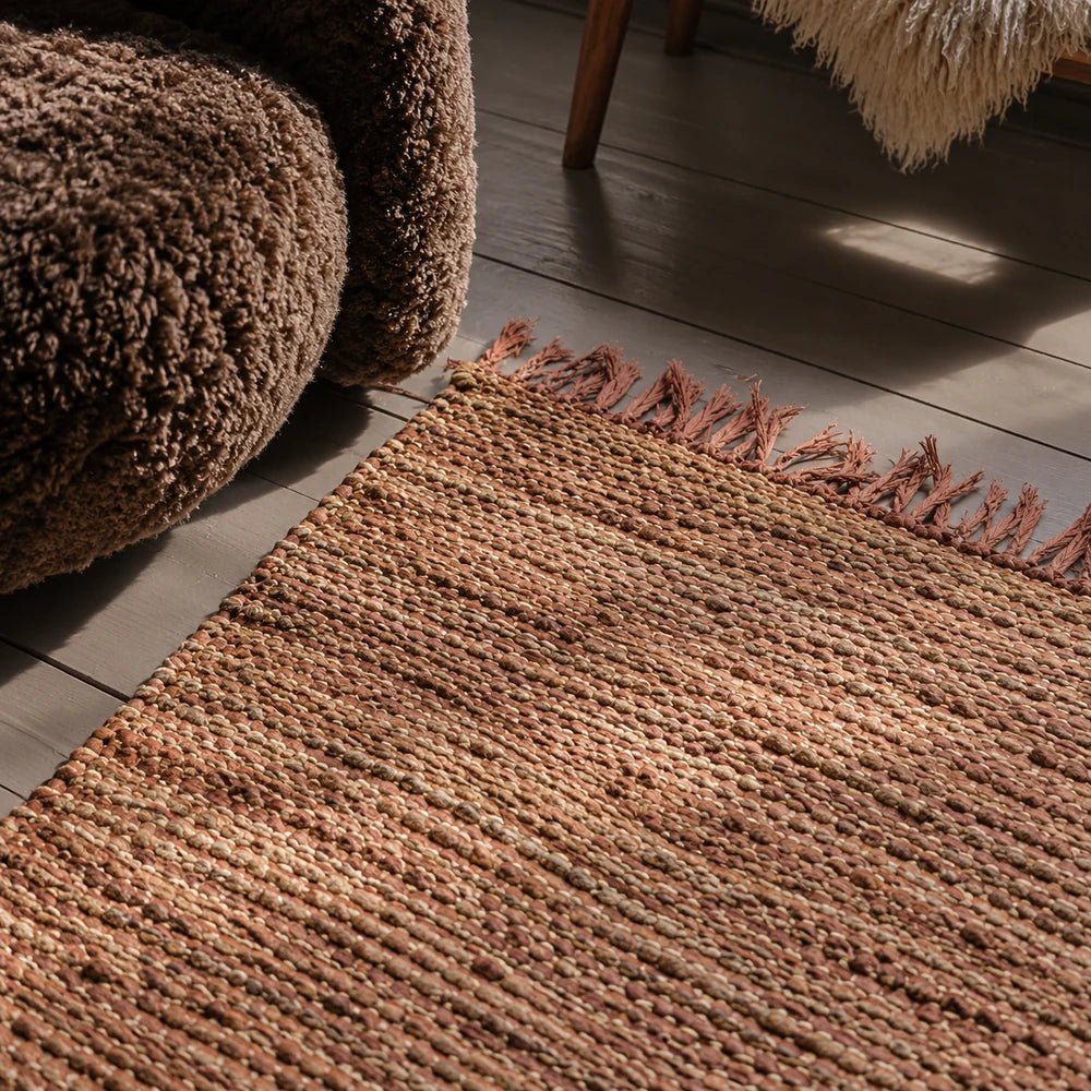 Kenzie Leather Rug with rich brown patchwork texture, styled beneath neutral furniture in a warm contemporary living room with layered natural materials.