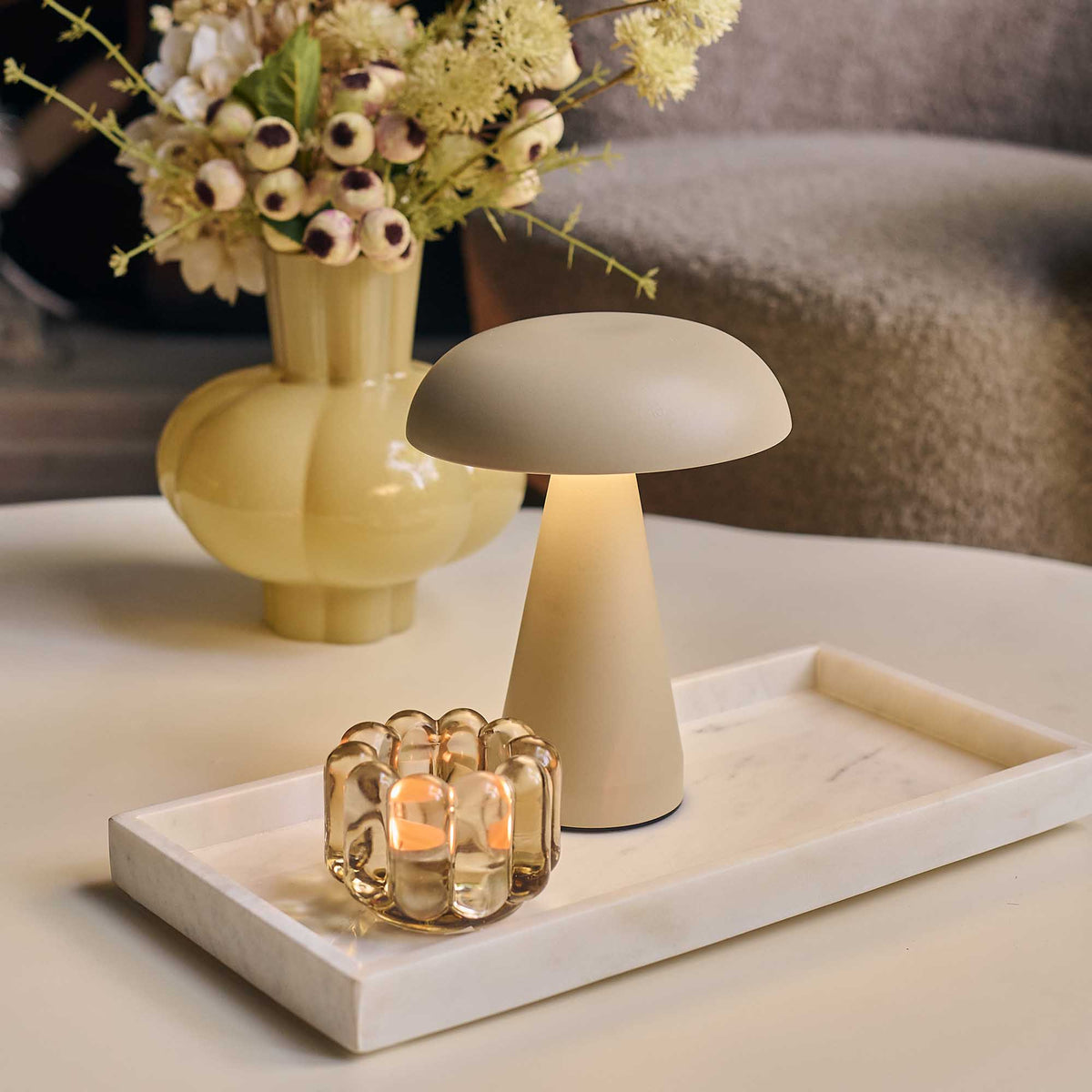 Mushroom-shaped lamp on a tray with a vase of flowers in the background