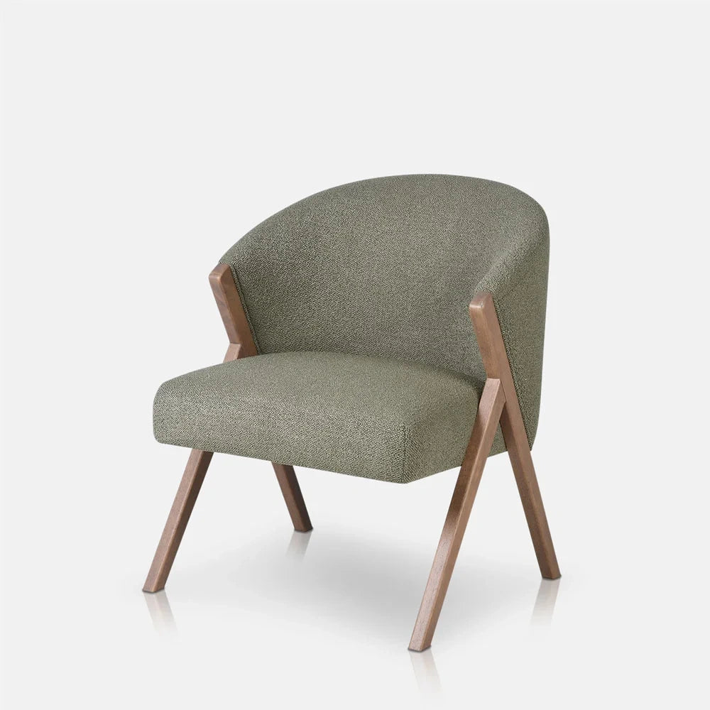 Lyndon Curved Accent Chair in pistachio combines a curved green upholstered back and cushioned seat with a warm wooden frame, shown from an angled view.