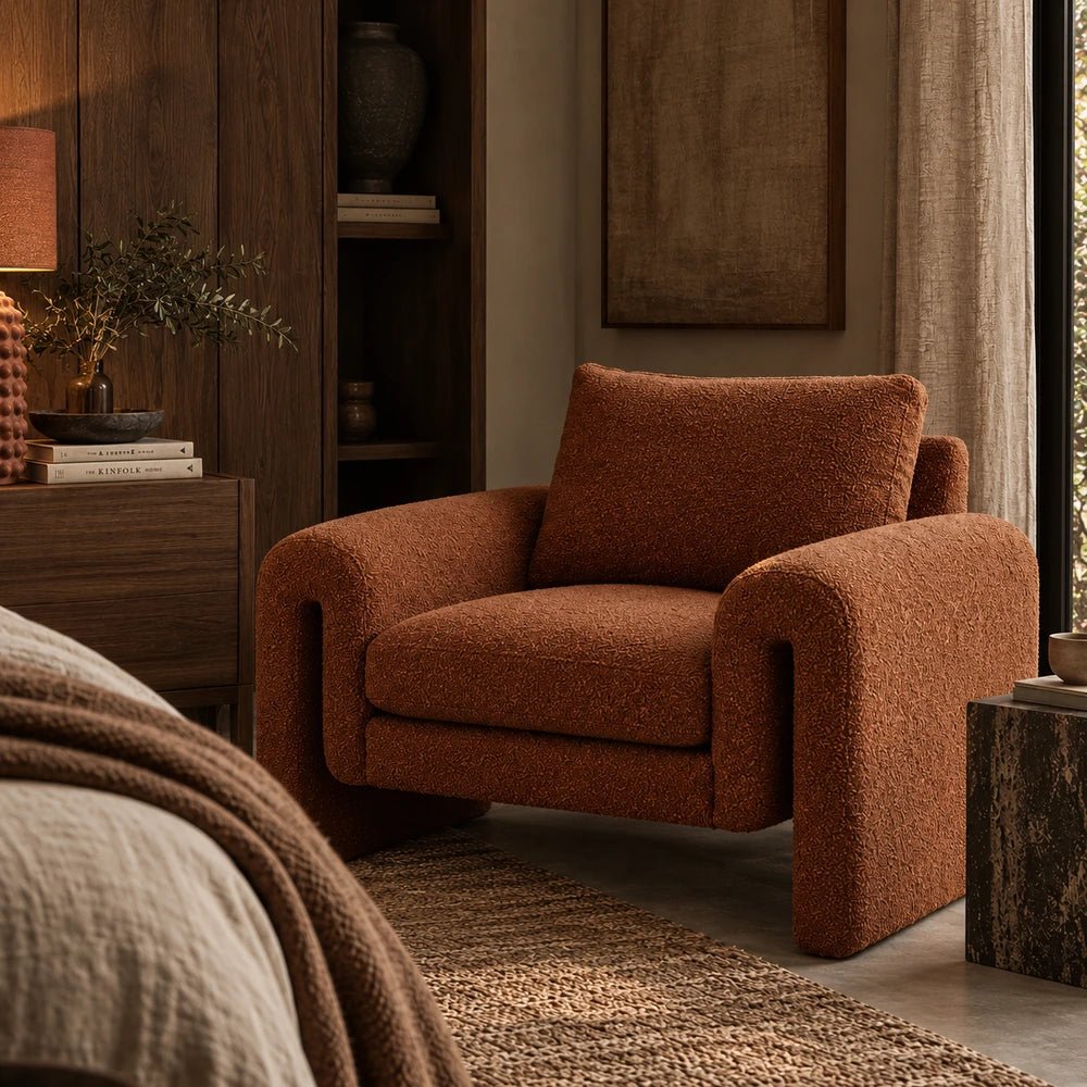 Manhattan Boucle Armchair in rich rust textured upholstery, styled in a warm living room with layered neutral furnishings and contemporary decorative accessories.