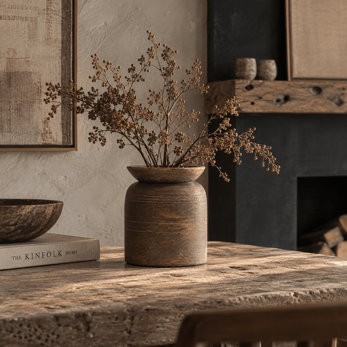 Massin Vase Medium in rich earthy brown ceramic, styled with natural stems on a layered shelf among warm neutral decorative objects and textures.