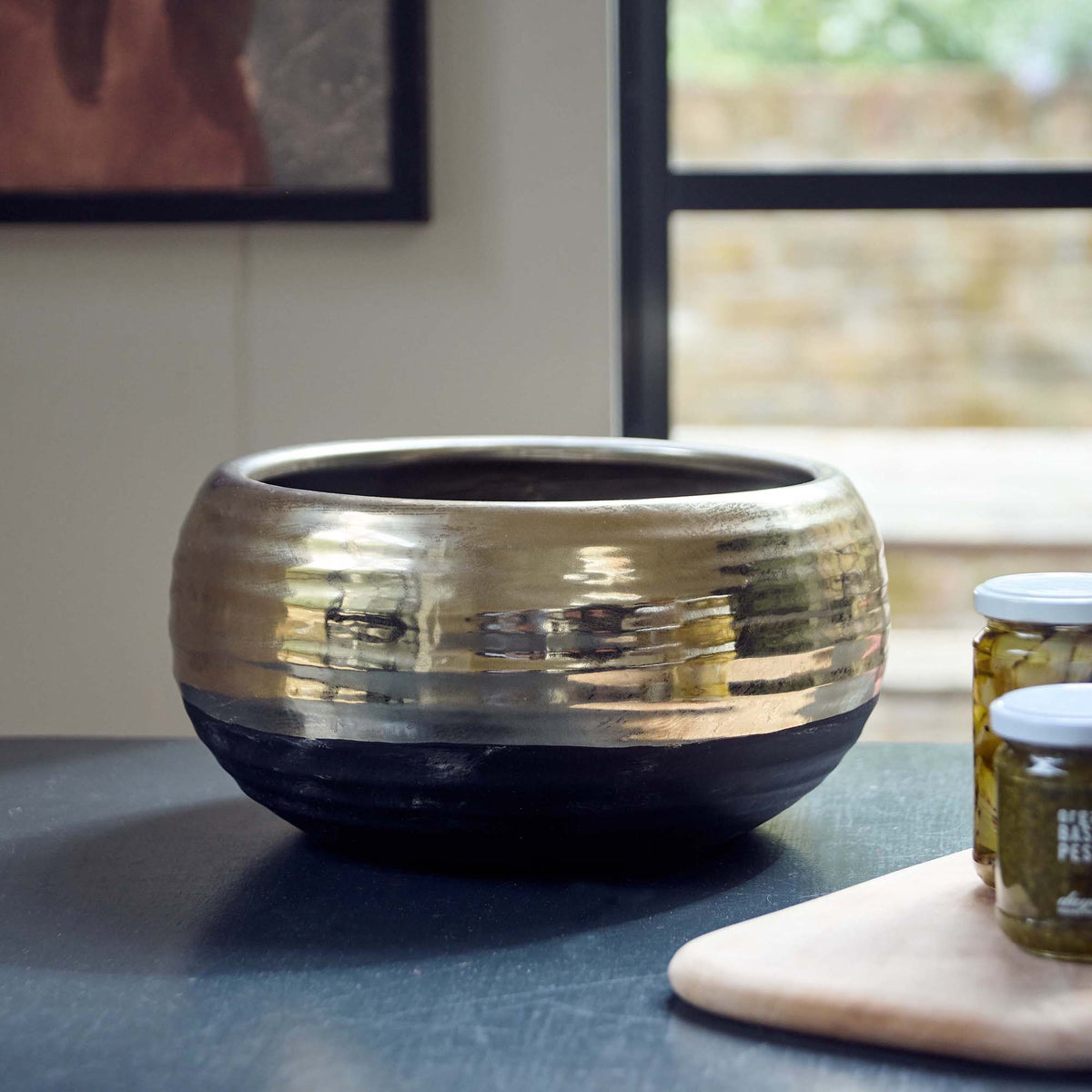 The Merritt Stone Decorative Bowl on a dark grey surface next to a pale marble chopping board.