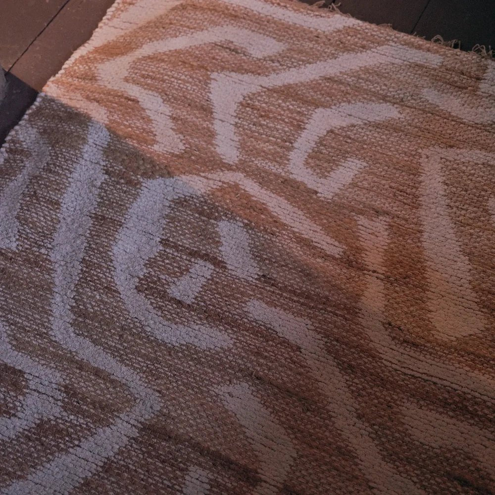 Montgomery Chenille Jute Rug reveals a cream and warm tan abstract pattern in close-up, with a textured woven surface and softly contrasting curved motifs.