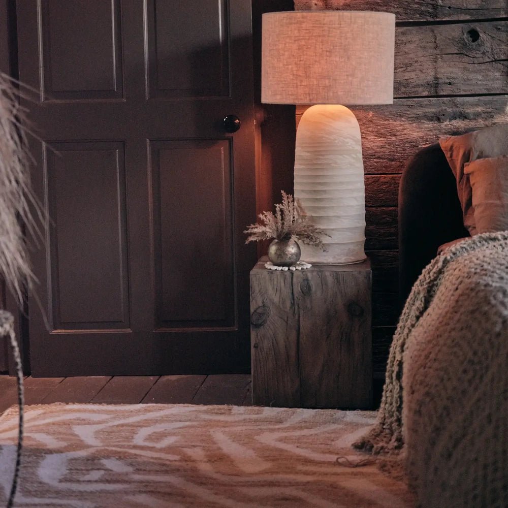 Montgomery Chenille Jute Rug brings a cream and tan abstract pattern to a living room floor, styled beside a sofa, wooden stool and warm lamp.