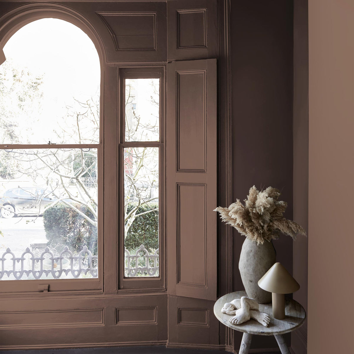Abigail Ahern Oaken Cask paint – a sumptuous rich brown with red undertones enveloping a beautifully styled room with large wooden shuttered window