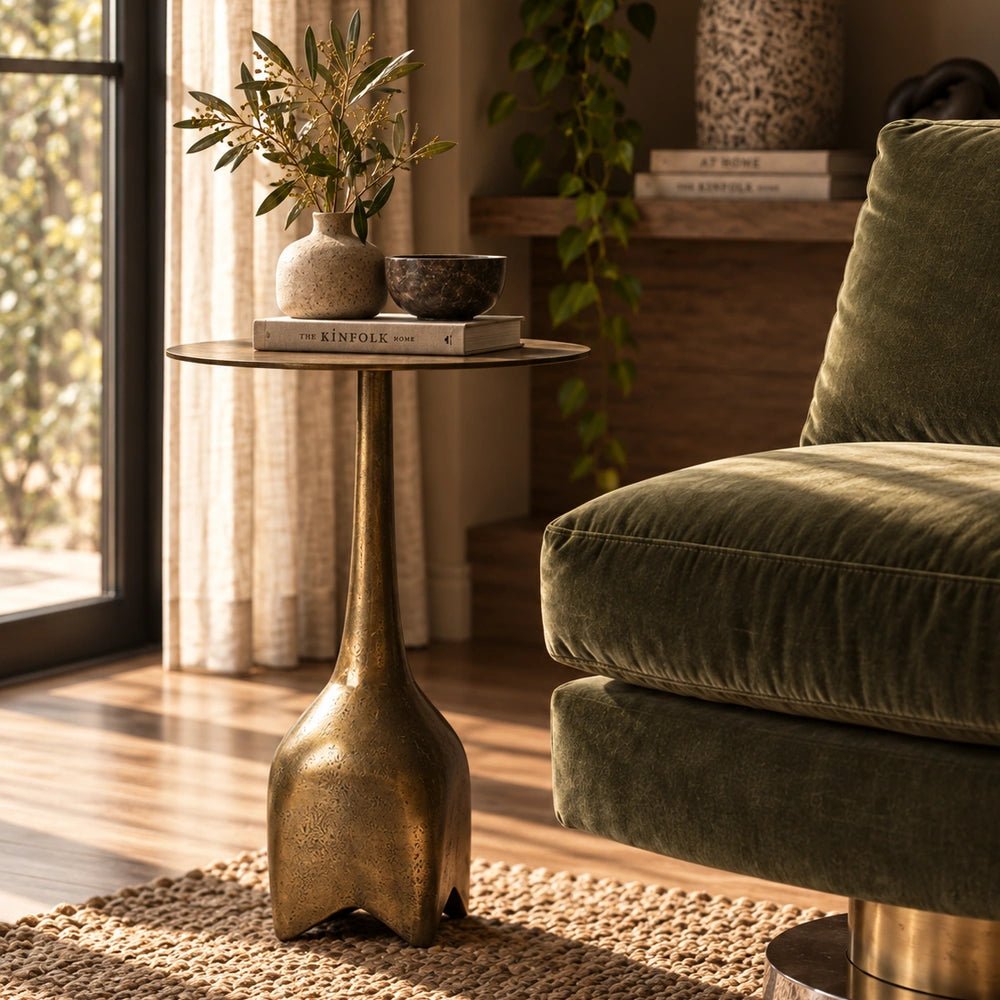 Oren Side Table in warm gold metal, styled beside neutral seating in a layered contemporary room with sculptural lighting and decorative accessories.