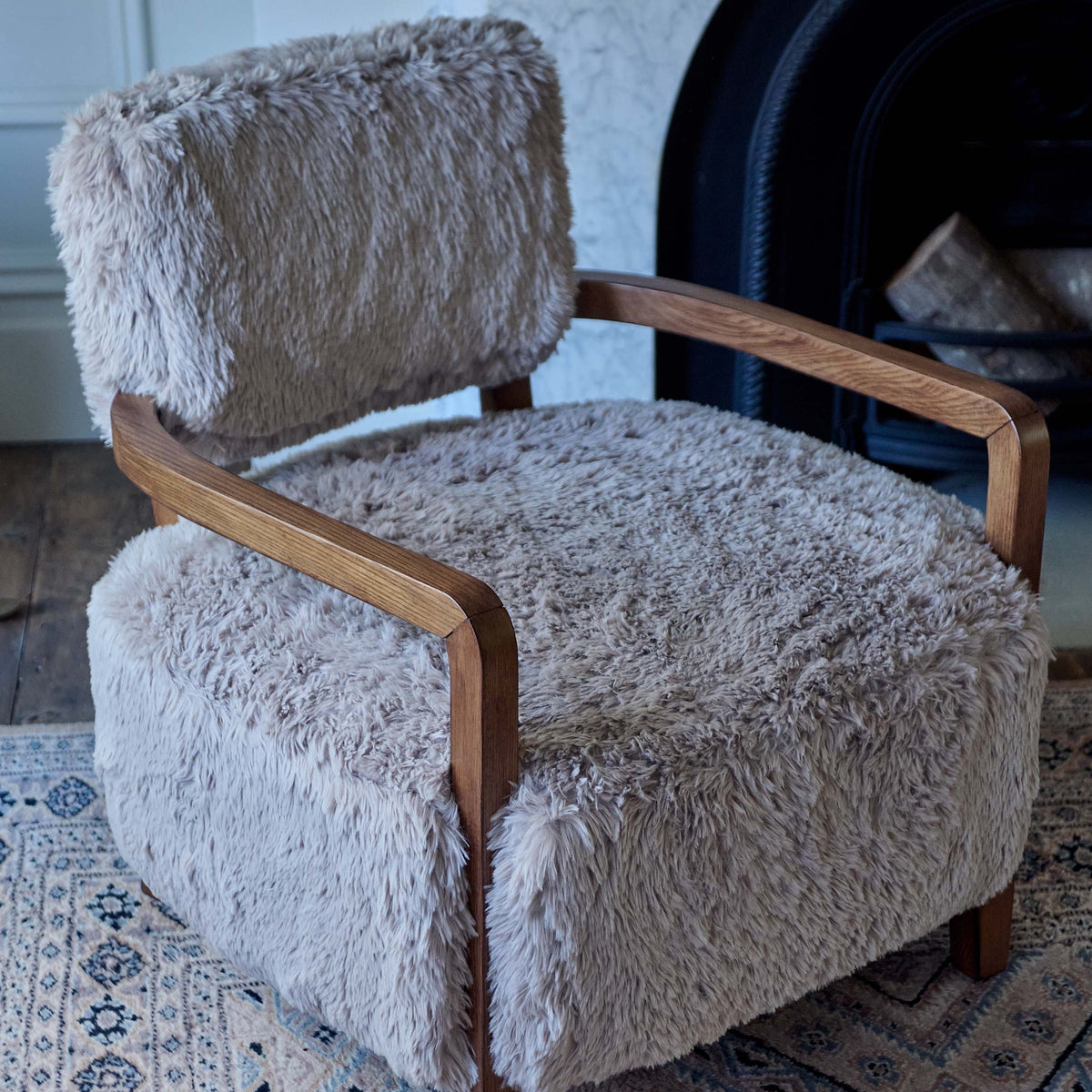 Luxury faux fur armchair featuring a soft textured upholstery, rounded sculptural silhouette, and contemporary organic design with exposed wooden arms complimenting warm neutral tones for modern living spaces.