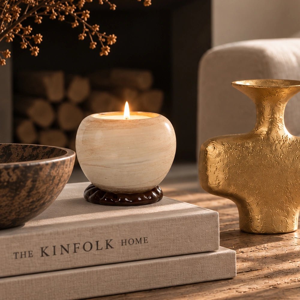 Ravello Glass Candle Holder, Smoke glowing atop stacked books, styled beside sculptural decor and dried foliage in a warm, softly lit living room setting.