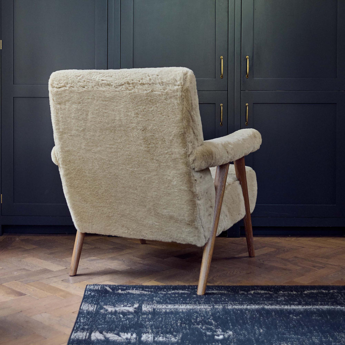 Back view of the The Robbins Faux Sheepskin Armchair, a super soft beige faux sheepskin armchair with padded armrests and a solid oak frame.
