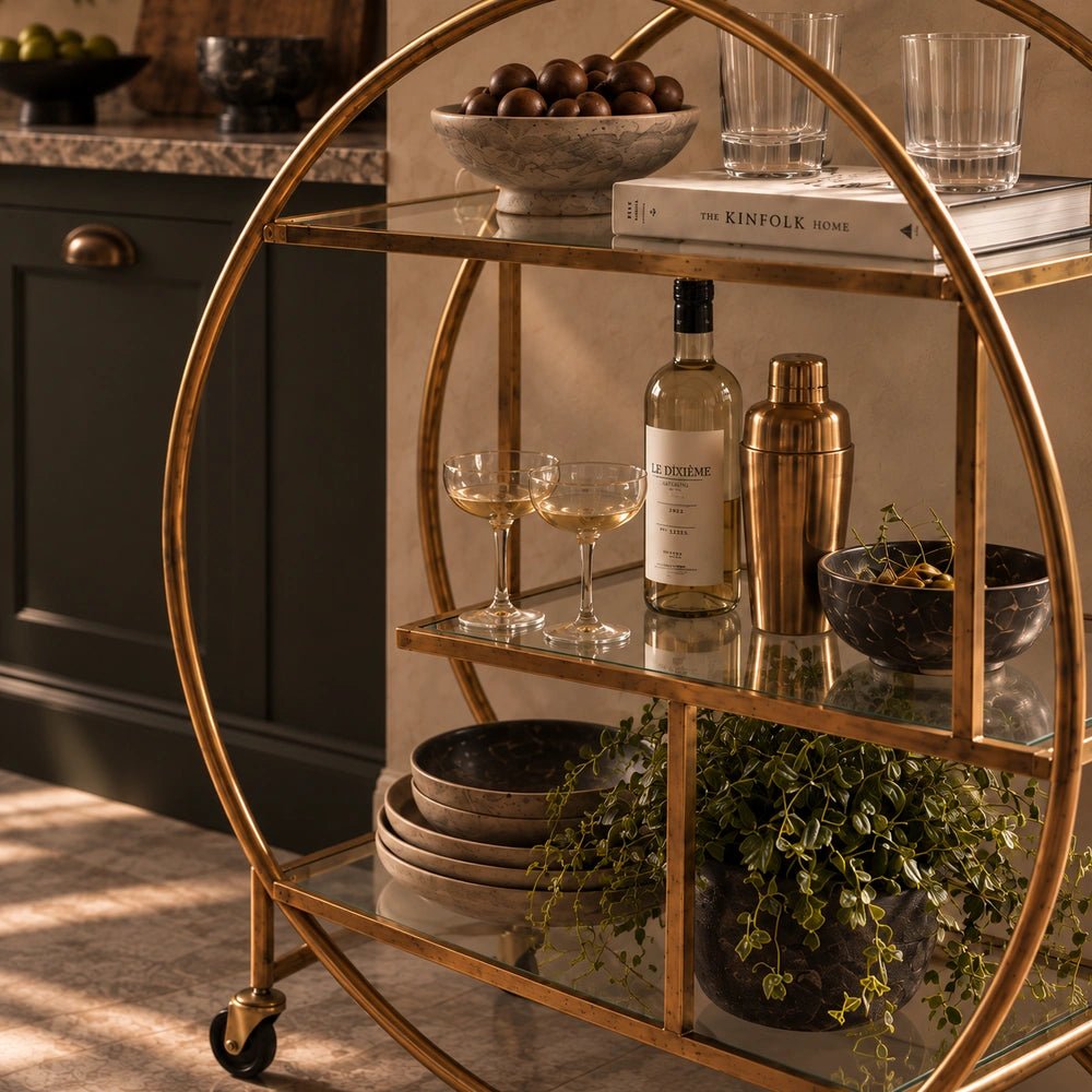 Rover Drinks Trolley with dark metal frame, styled with bottles, glassware and decorative accessories in a warm neutral interior corner.
