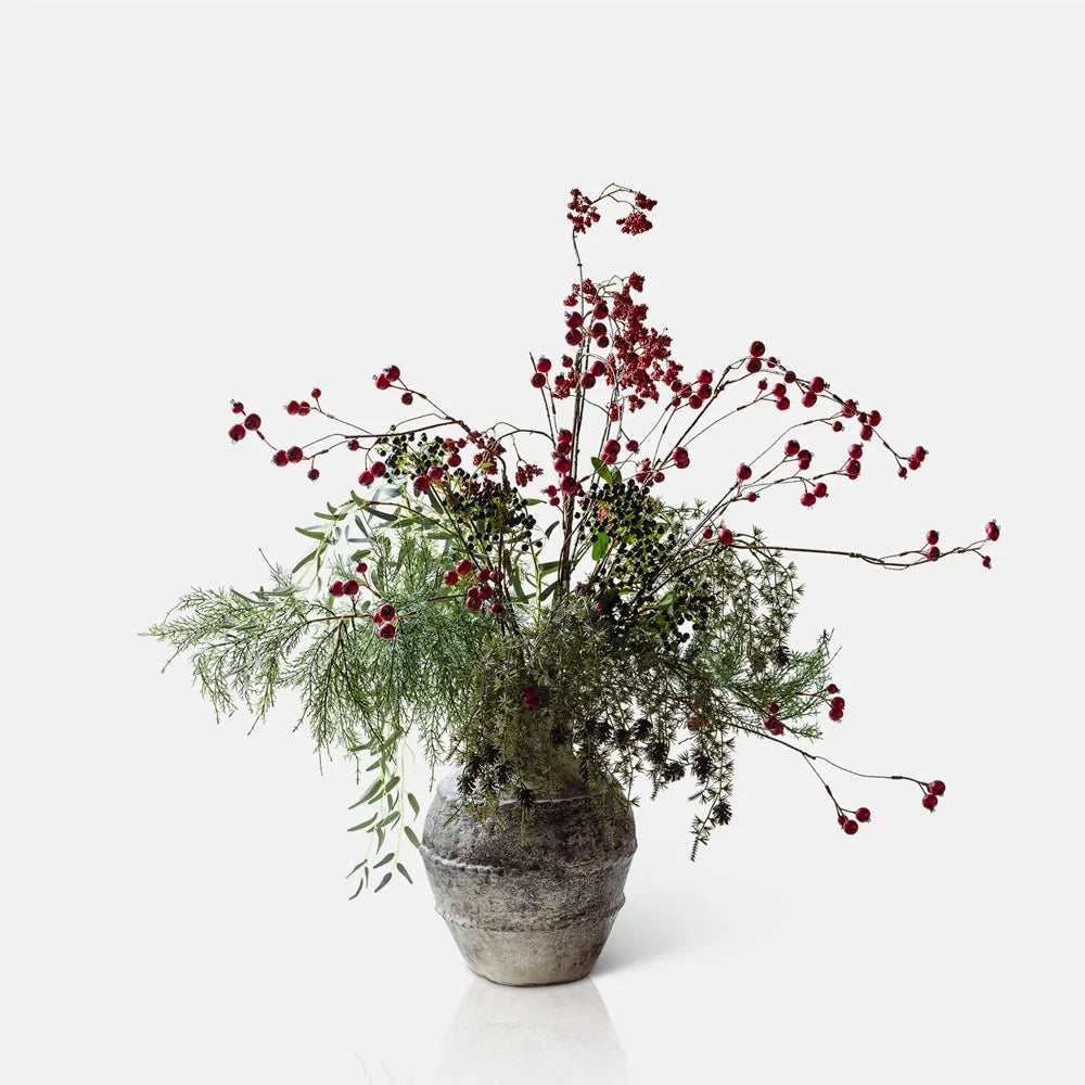 Ruston Artificial Bouquet combines red berry branches, dark seed clusters and airy green foliage in a rounded grey vase with a textured surface.