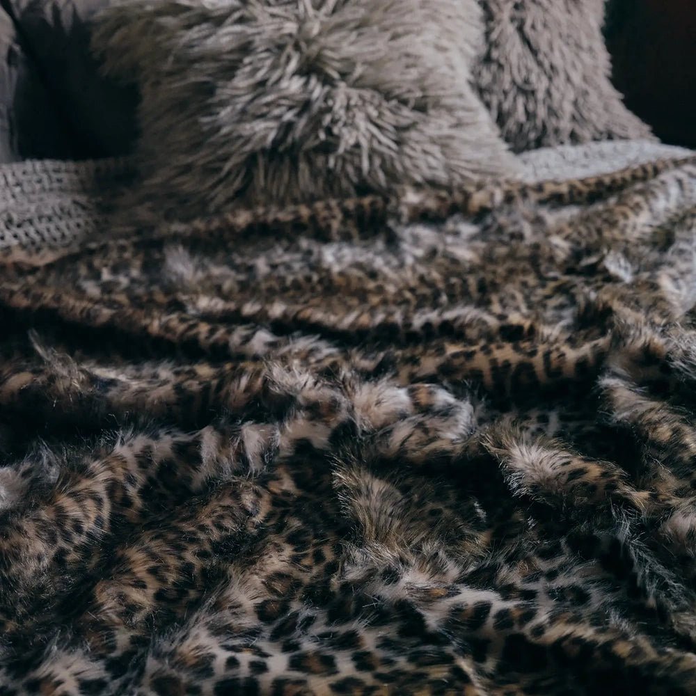 Savannah throw shown close up, revealing soft raised pile and a mottled animal print in brown, cream and dark tones draped across textured upholstery.