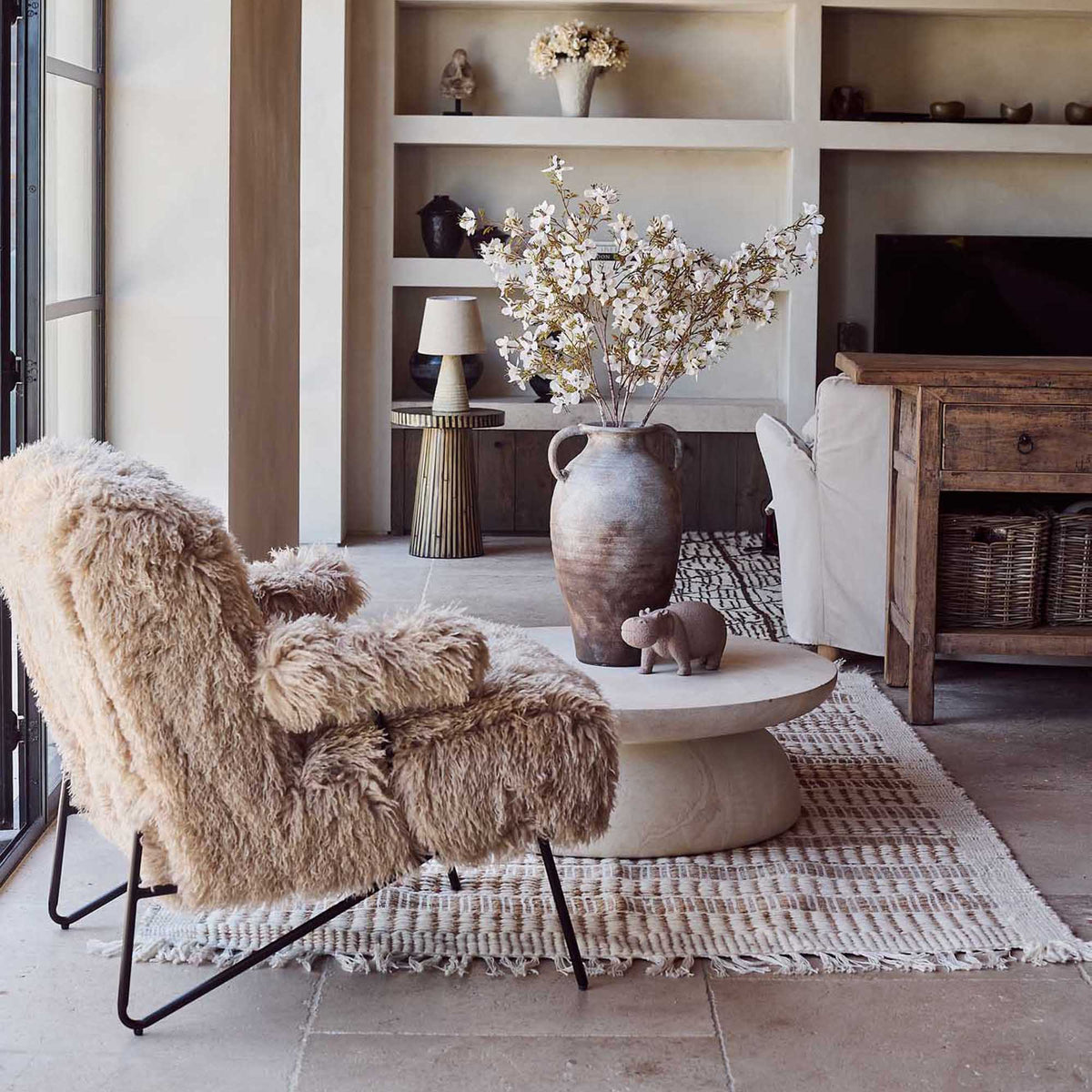 Selma faux fur armchair upholstered in soft cream faux fur with a curved contemporary silhouette, rounded backrest and generously cushioned seat. Luxury accent chair designed for living rooms, bedrooms and reading corners, bringing warmth, texture and comfort while adding sculptural form and understated elegance to modern and eclectic interiors.