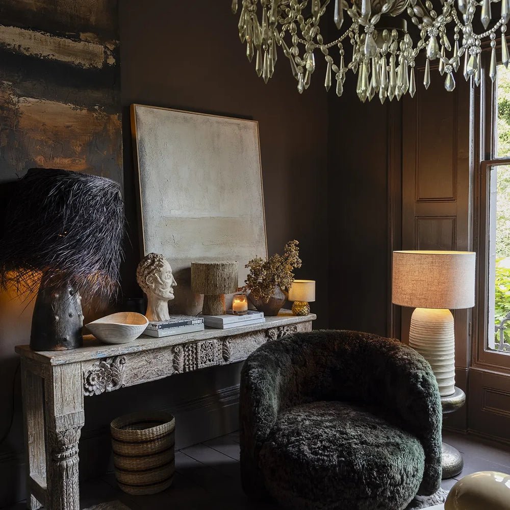 Serenity canvas art brings a pale abstract rectangle to a dark living room, displayed above a carved console beside sculptural objects, lamps and a rounded chair.
