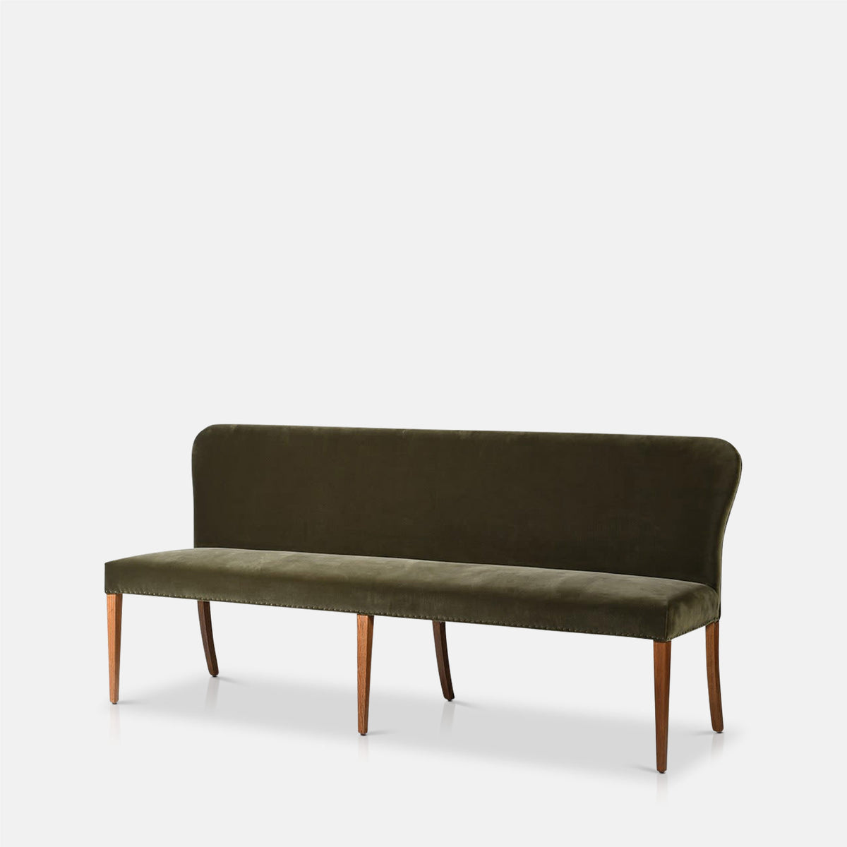 Abigail Ahern Thorne Velvet Dining Bench shown from an angled view, highlighting its plush upholstered seat, tall cushioned backrest and solid oak wood frame.