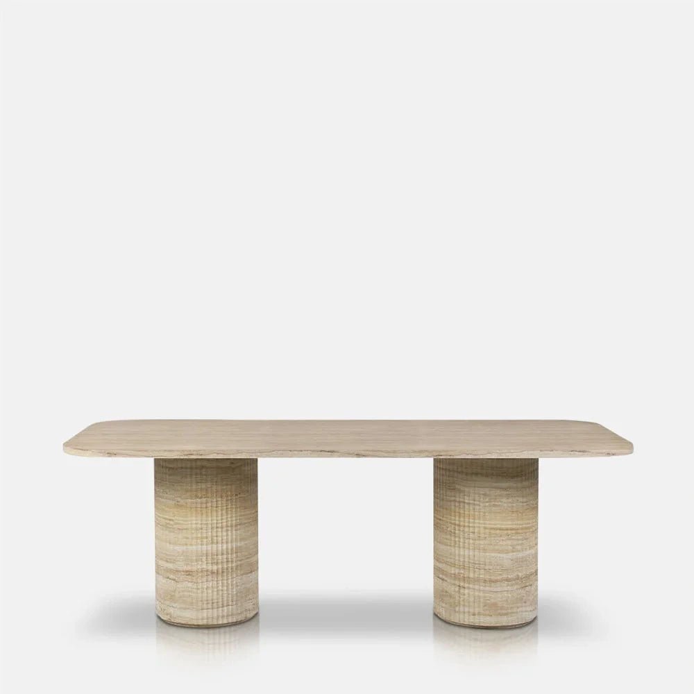 Westwood faux travertine dining table shown from the front, with a long pale rectangular top, rounded corners and two cylindrical bases patterned in beige tones.
