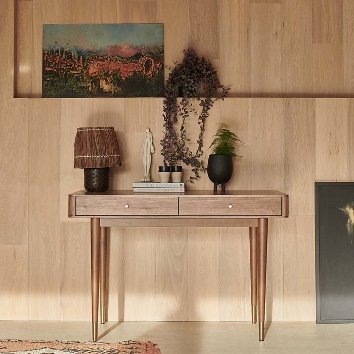 The Winslow Desk, a warm brown wooden desk in mid century style design, with gold metal detailing.