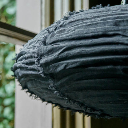 A close up of a medium fabric black lampshade in an oval shape. Crinkled oval shaped fabric pendant shade in black with short tasseled lines on its surface