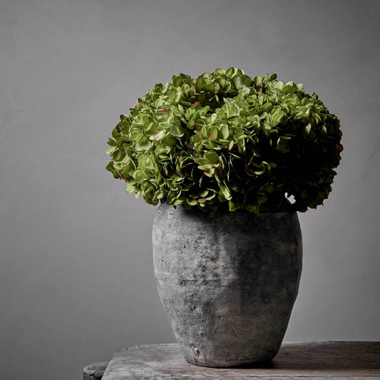 Artificial green hydrangeas in a large grey stoneware vase. Pair with some contrasting Abigail Ahern faux foliage for a beautiful injection of colour to any room. 
