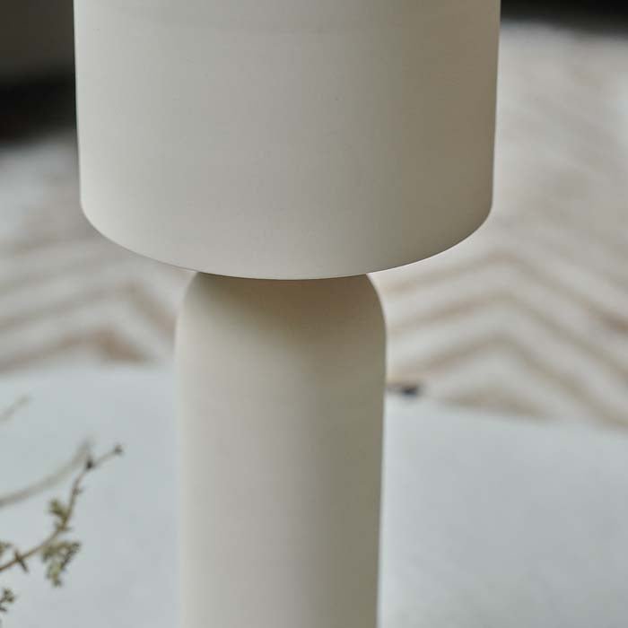 A close up of the Barkly Table Lamp. A sleek matte cream metal table lamp with curved shade and smooth tapered base.