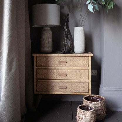 Rattan chest of drawers with3 drawers, styled with a table lamp and tall grey vase. Drawers that add extra storage space in your bedroom.