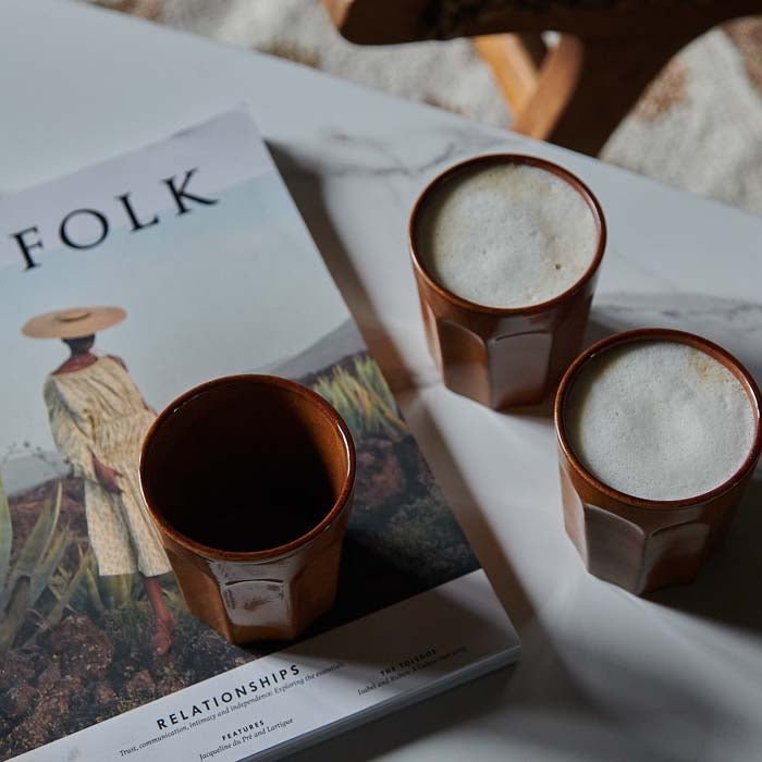 A view from above of the Franco Stoneware Mug - Set of 4 filled with coffee, next to a book.