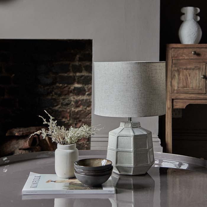 Table lamp with grey shade and white ceramic base.