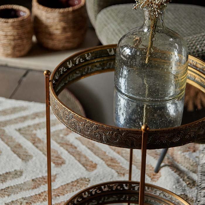 Ritson Mirrored Side Table, a two tiered, round mirrored side table with a bronze frame, styled with a rustic glass vase.