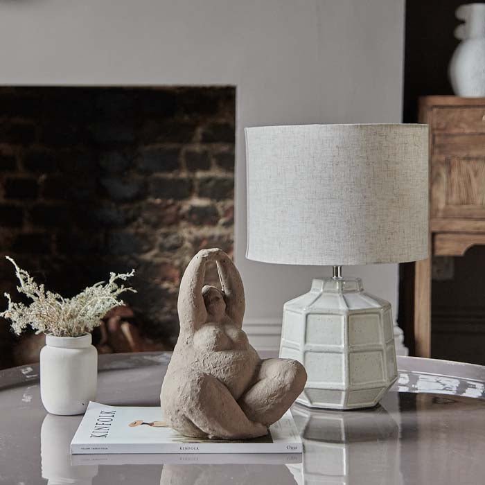 Enamel coffee table with cement sitting figurine, faux plant and a table lamp.