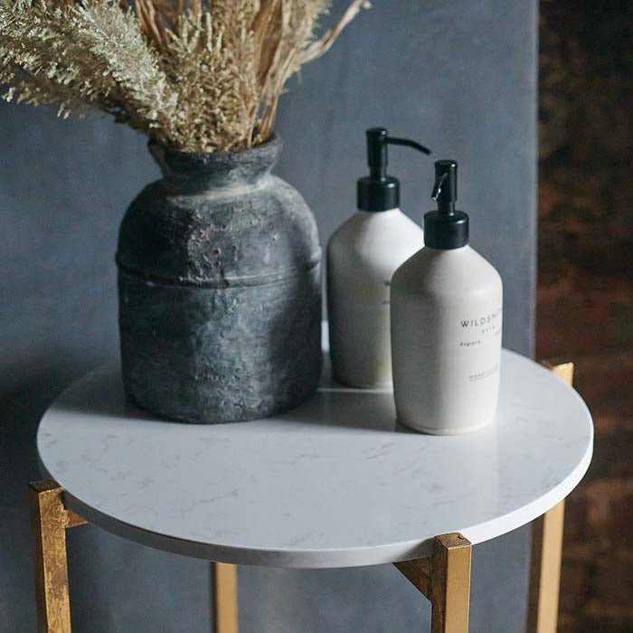 The Snowden Occasional Table, a round side table with gold metal legs and frame, topped by white faux marble table top.