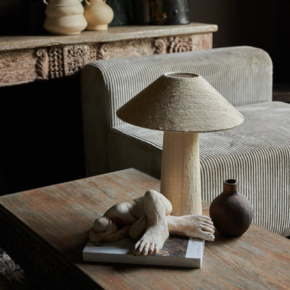A fabric table lamp in a neutral colour styled on a coffee table with a female sculpture. Designer style table lamp to add a unique style to your home. 