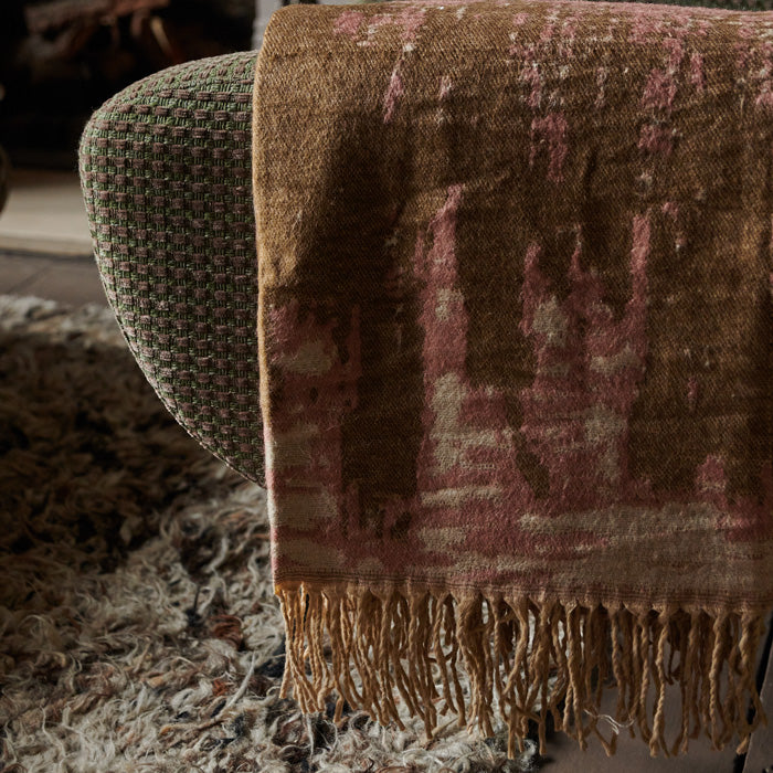 Pink and brown tasseled throw draped over the arm of an armchair