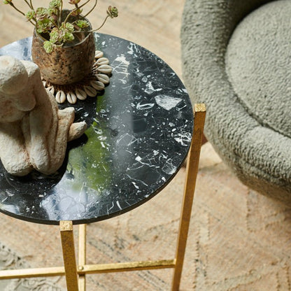 Black and white marble effect side table with a golden frame sat on a brown jute rug