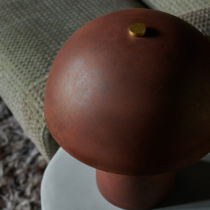 Rust red metal table lamp shade with gold screw at top.