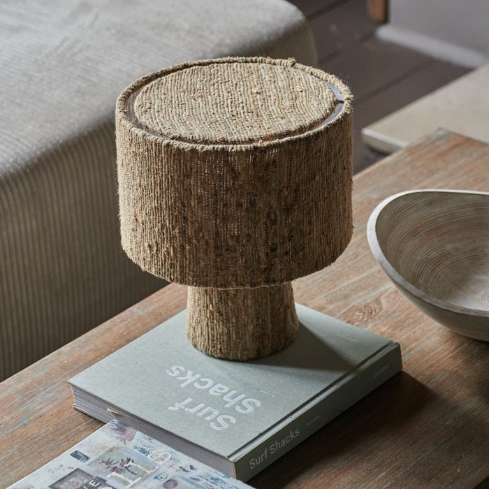 Table lamp covered in woven brown textured silk fabric, with round drum shade and short base. Table lamp made from fabric.