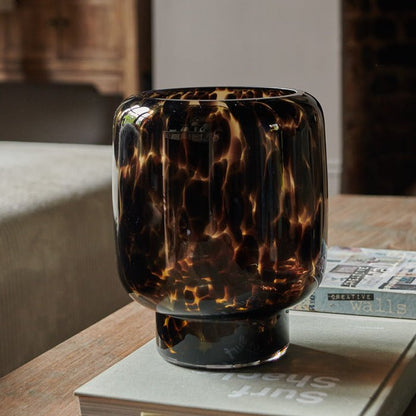 Amber and brown marbled glass vase sat on a wooden coffee table