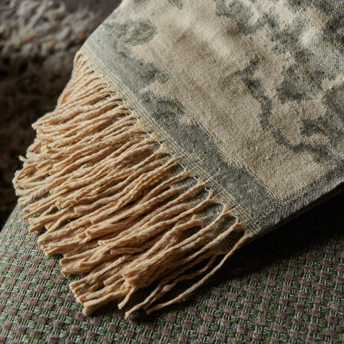 Brown tassels on the edge of a cream, brown and grey patterned throw
