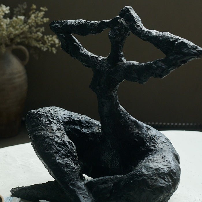 Resin sculpture of sitting figure, with rustic textured matte black finish. Sculpture in the home adds unique style to your home decor. 
