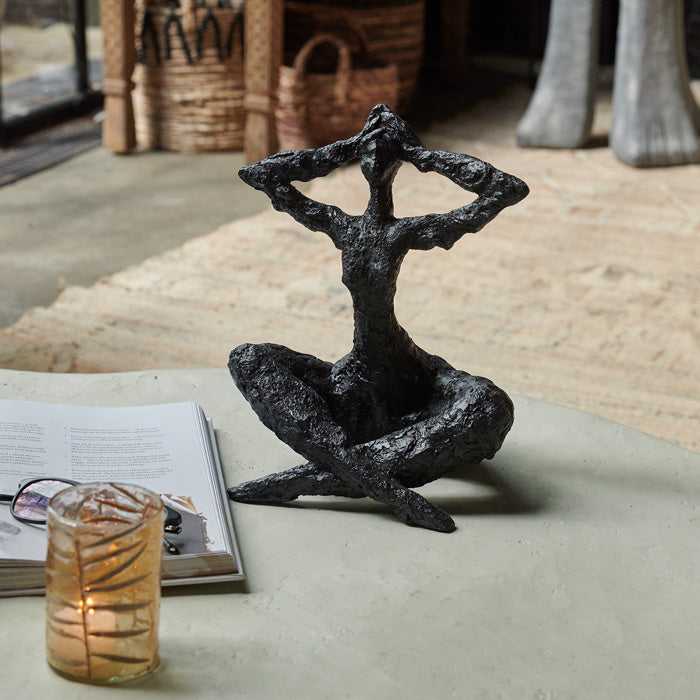 Figurative sculpture in seated position, crafted from resin with matte black finish.