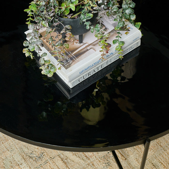 Shiny black enamel tray table with a stack of books in its centre
