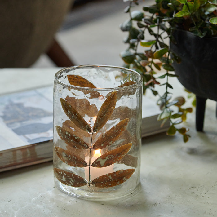 Clear glass candle holder, with organic recycled look, decorated with brown leaf design.