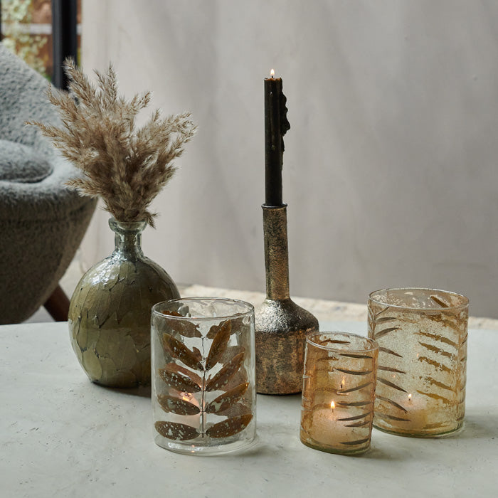 Assorted glass and metal candle holders on a white coffee tale.
