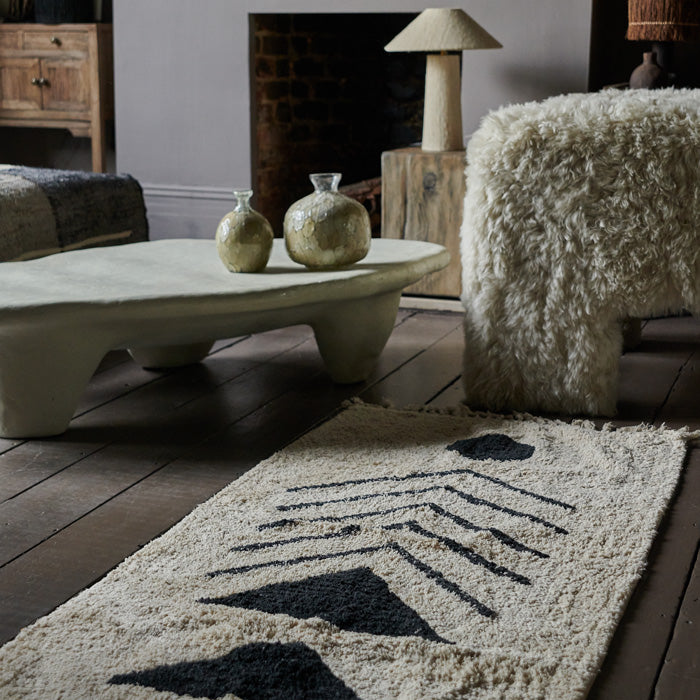 Cream and black tufted cotton rug with abstract landscape motif.