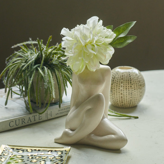 Sitting female figure vase in cream with a large flower placed in its neck